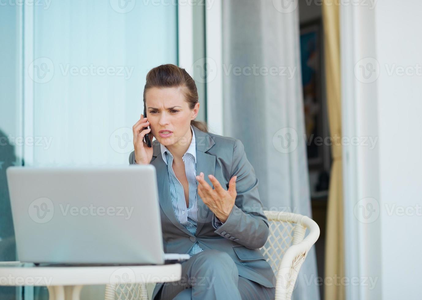 besorgte Geschäftsfrau, die Handy auf Terrasse spricht foto