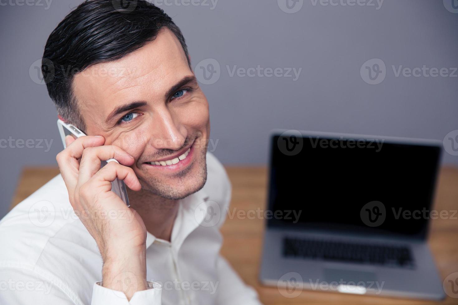 lächelnder Geschäftsmann, der am Telefon spricht foto