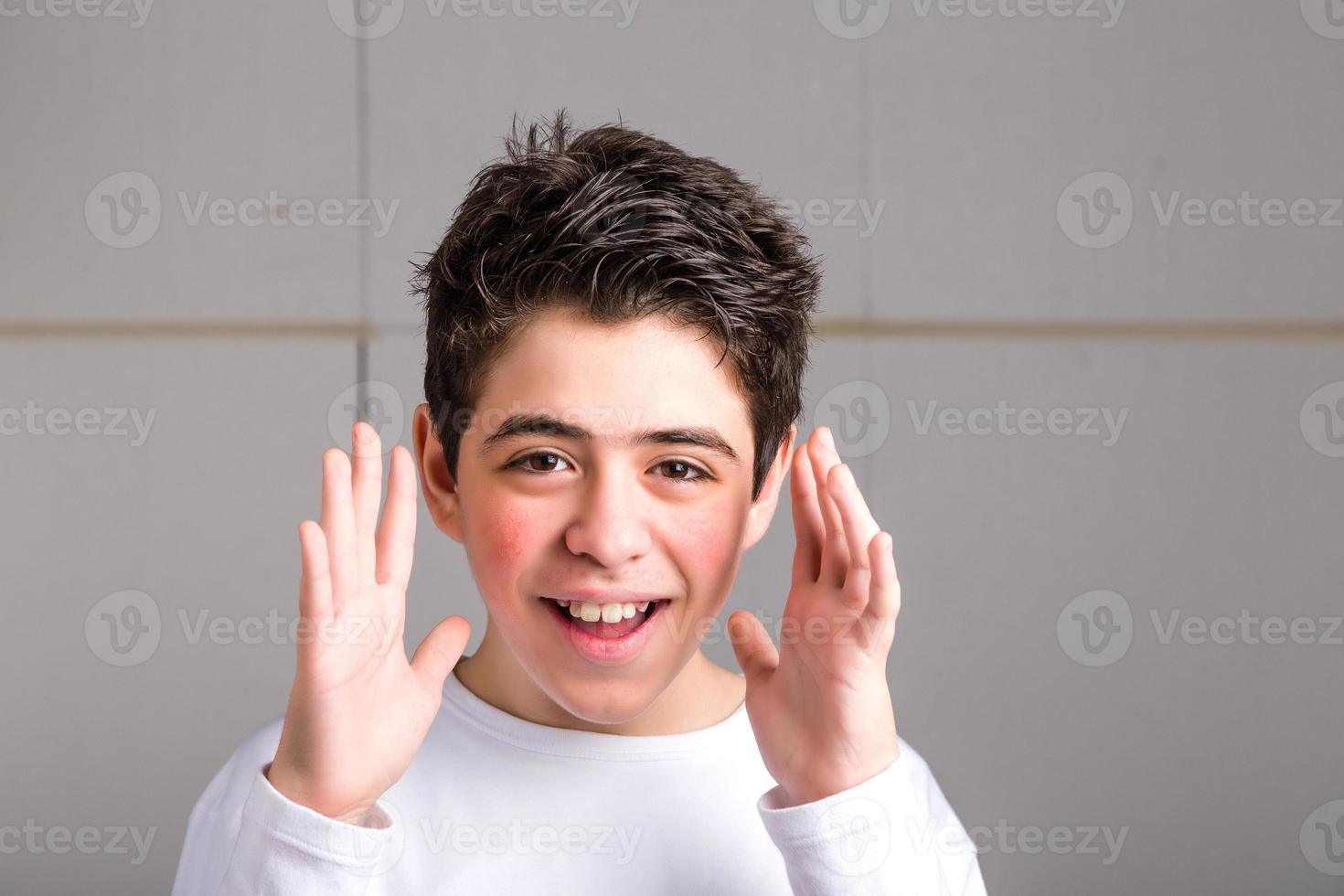 kaukasischer Junge mit glatter Haut, der offene Hände entlang des Gesichts winkt foto
