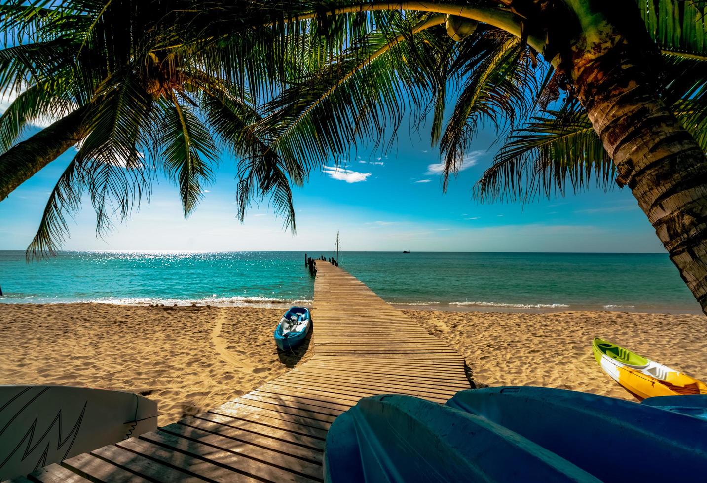 schöne aussicht tropischer paradiesstrand des resorts. Kokospalme, Holzbrücke und Kajak im Resort an einem sonnigen Tag. sommerferienkonzept. sommergefühl. Goldener Sandstrand des Resorts mit blauem Himmel. foto