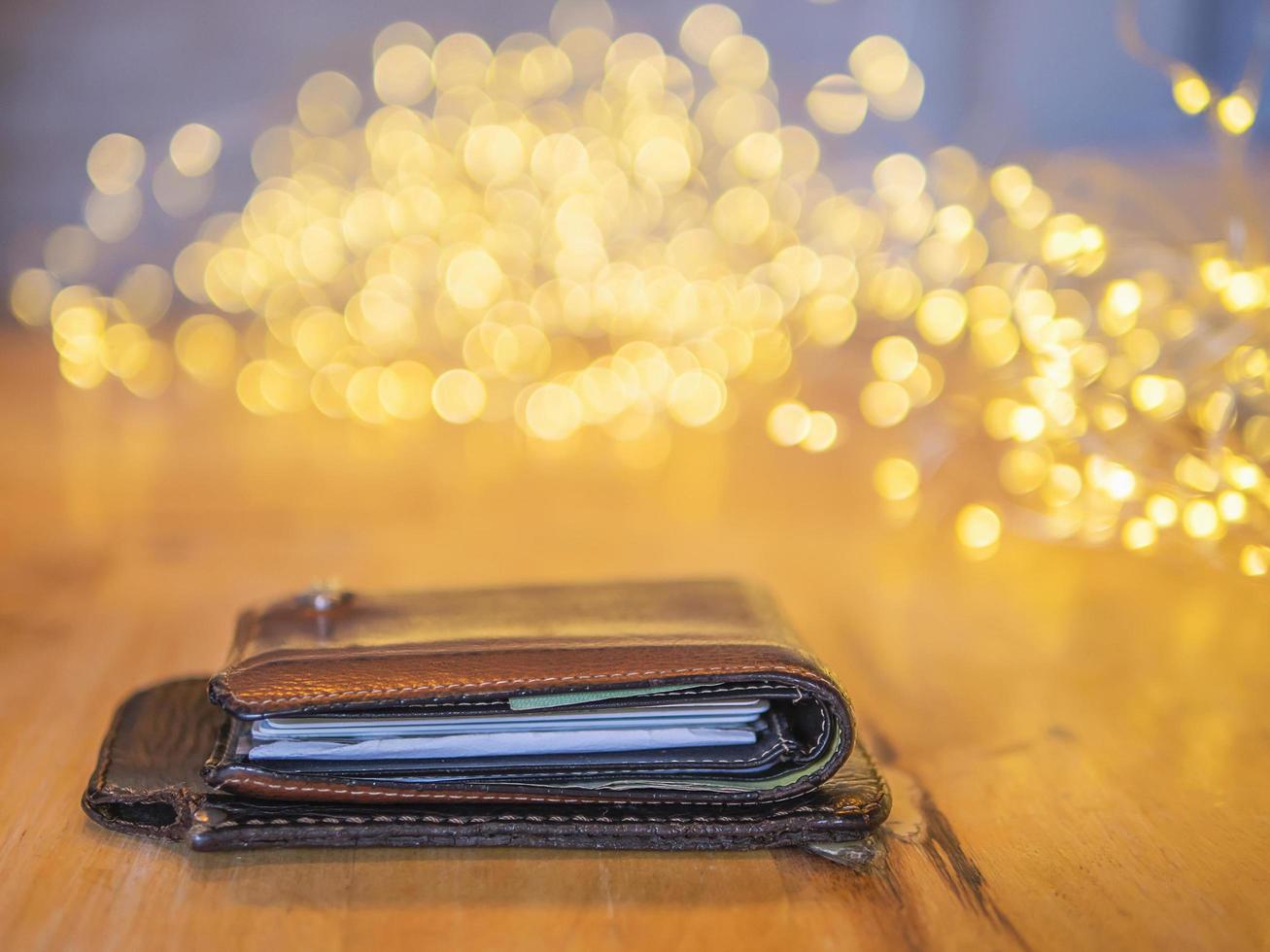 Portemonnaie und mobile Abdeckung Leder auf Holztisch mit kleinem dekorativem hellem Bokeh-Hintergrund foto