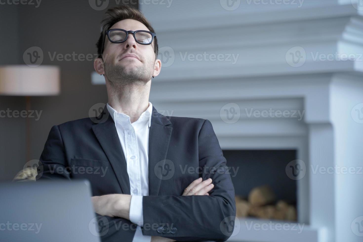 Mediativer deutscher Geschäftsmann sitzt mit geschlossenen Augen am Schreibtisch und ruht sich von der Computerarbeit aus foto