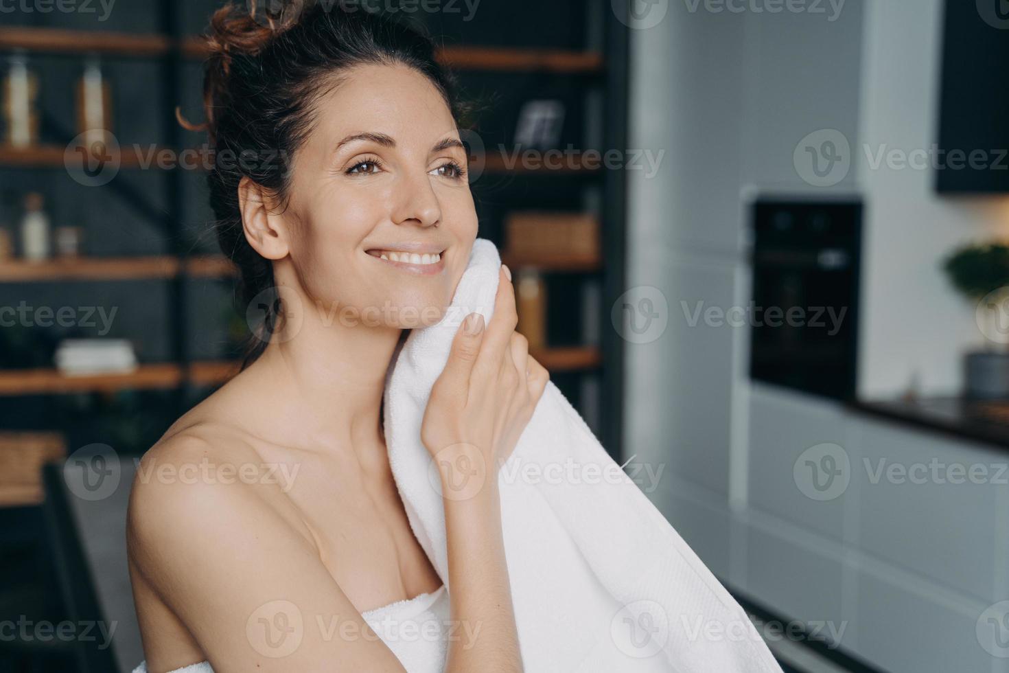 Attraktive hispanische Frau wischt sich nach dem Duschen zu Hause das Gesicht mit einem Handtuch ab. Beauty-Routine. foto