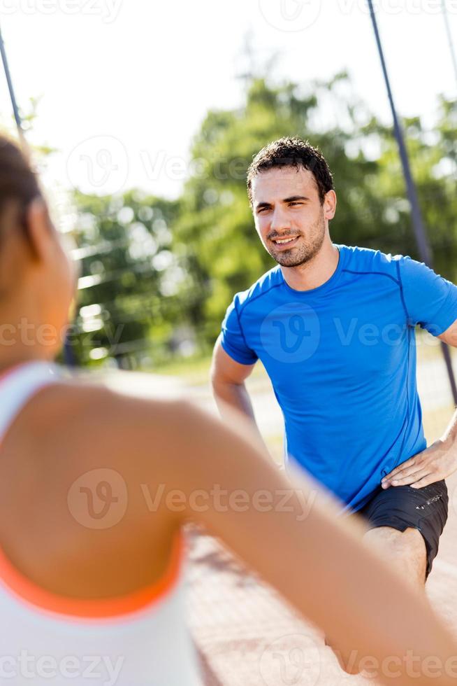 sportlicher Mann und Frau, die draußen an einem heißen Sommer strecken foto