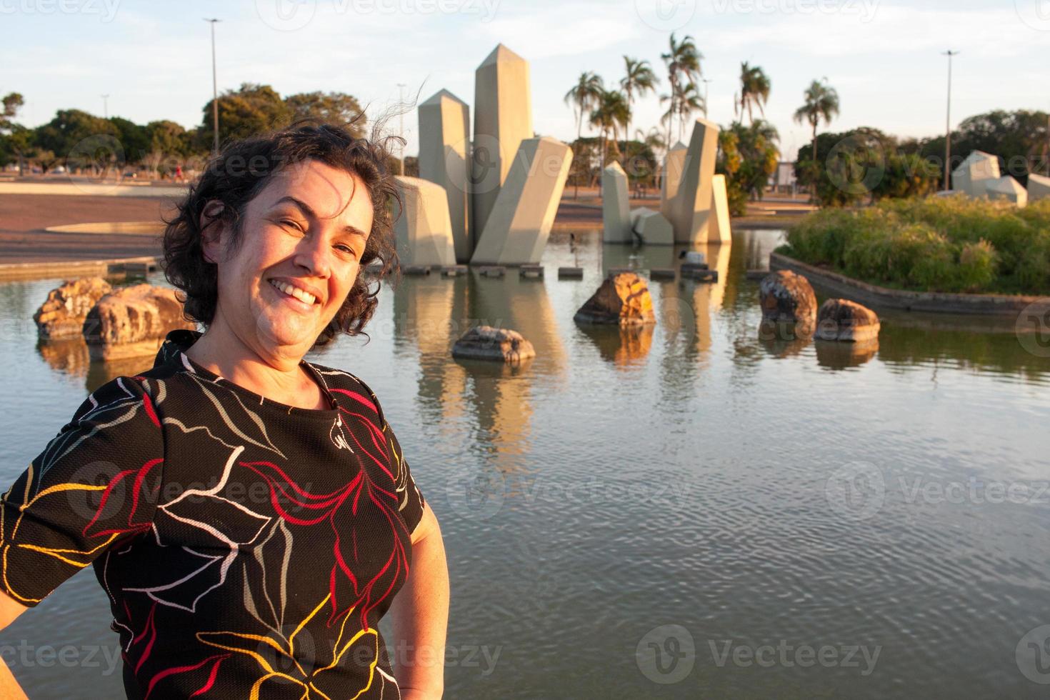 Reife Dame im Park an einem sonnigen Tag amüsiert sich mit Kristallen im Hintergrund foto