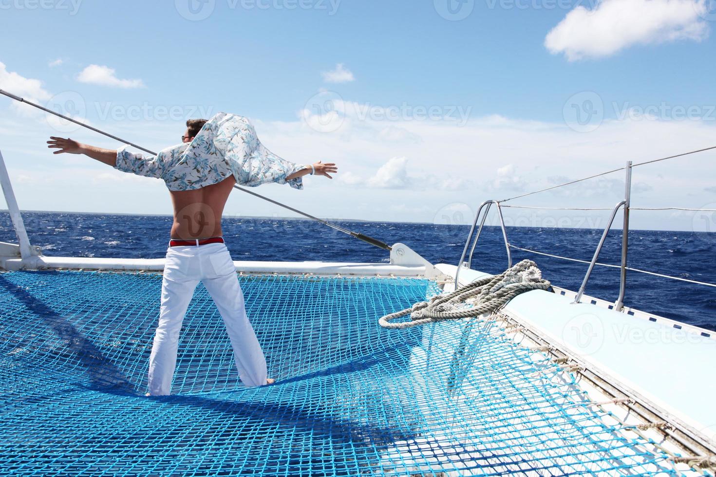 junger Mann, der sein Boot auf dem offenen Ozean segelt foto