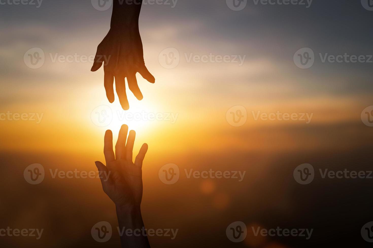 Silhouette des Erreichens, eine helfende Hand geben, hoffen und sich gegenseitig über unscharfen Sonnenuntergangshimmelhintergrund unterstützen. foto