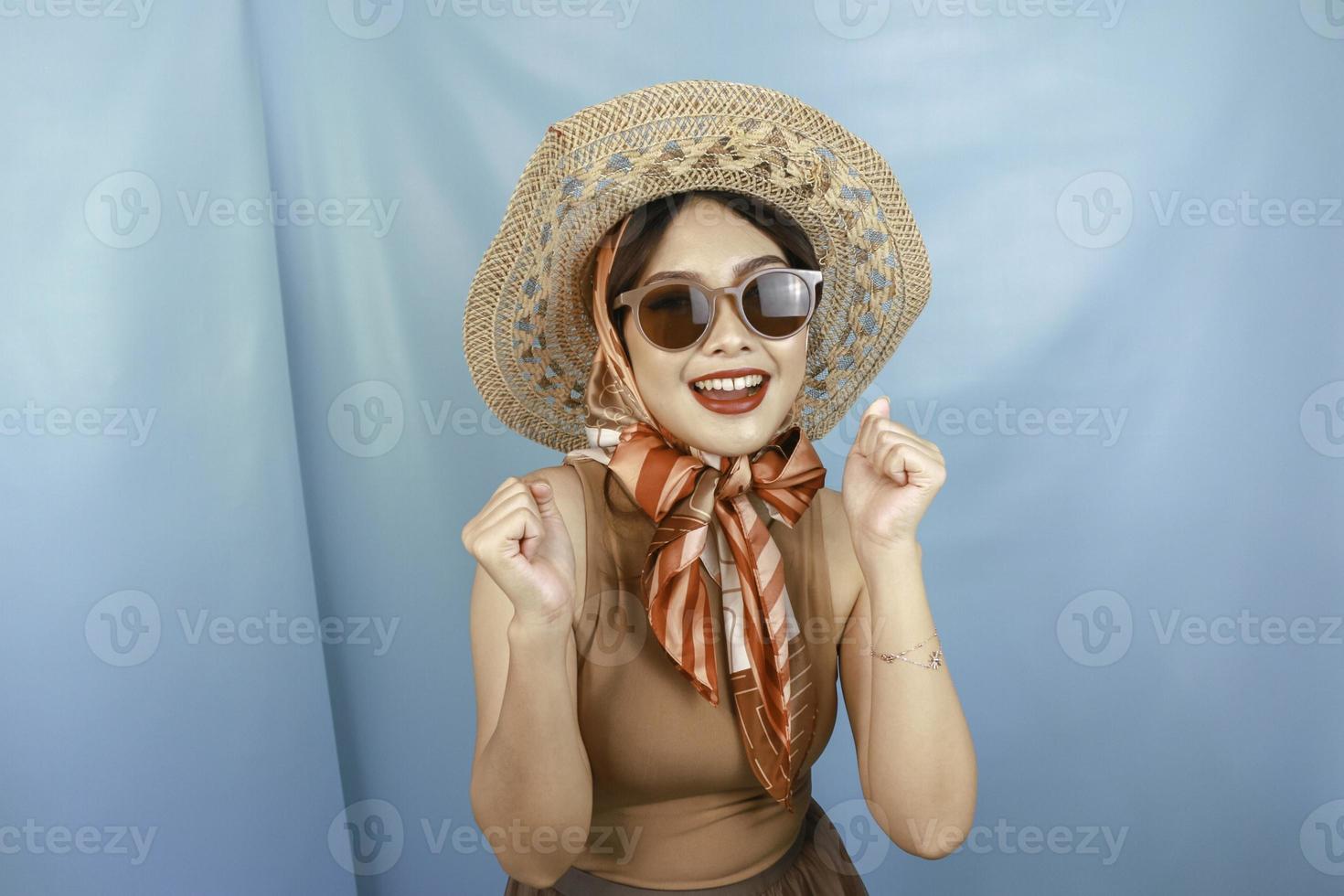 junge asiatische selbstbewusste und glückliche frau, die durch einen blauen hintergrund isoliert wird. foto