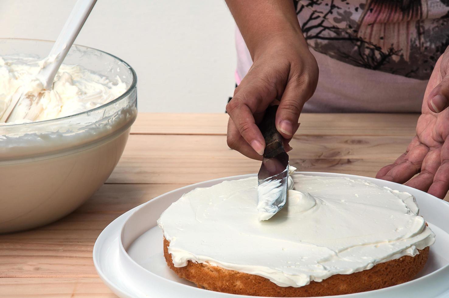 Buttercremekuchen mit Spachtel von Hand aufsetzen foto