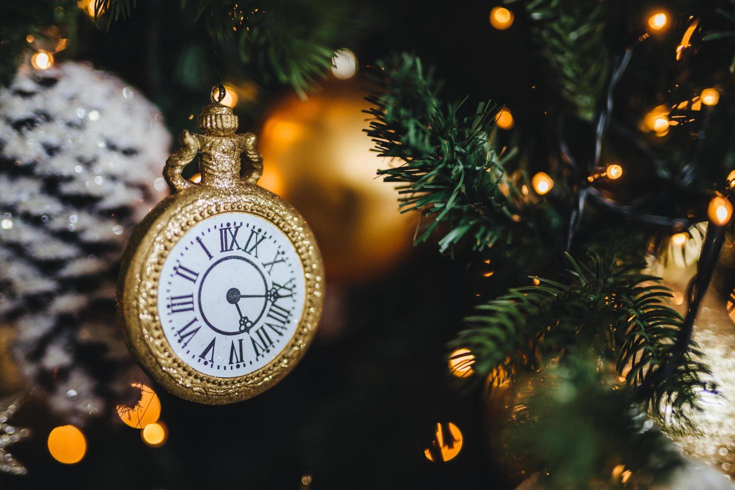 bild des geschmückten neujahrs- oder weihnachtsbaums mit girlanden und kugeln. Dekoration in Form einer Uhr symbolisiert den Beginn des neuen Jahres. ferien, feier, winterkonzept. foto