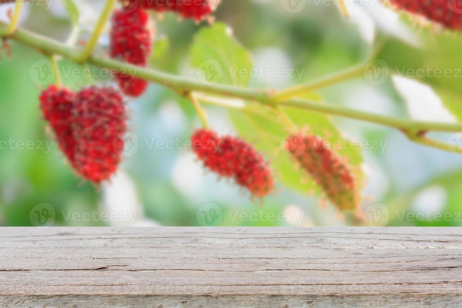 Holztisch mit rotem Maulbeerhintergrund foto