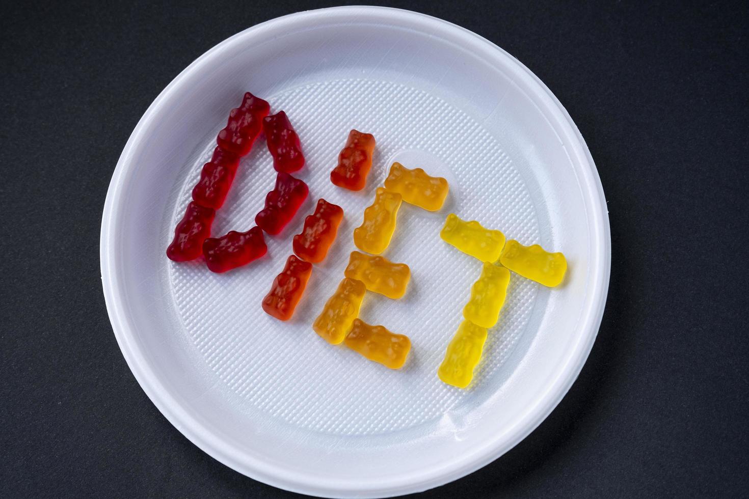 weiße Plastikplatte mit Textdiät aus süßem Gelee. süße Fruchtgummibärchen. gesunde ernährung, junk food, diät und schlankheitskonzept, draufsicht. foto