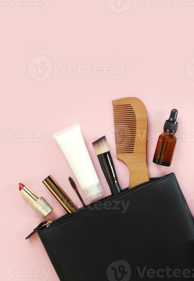 Make-up-Tasche mit dekorativer Kosmetik und Accessoires auf rosa Hintergrund foto