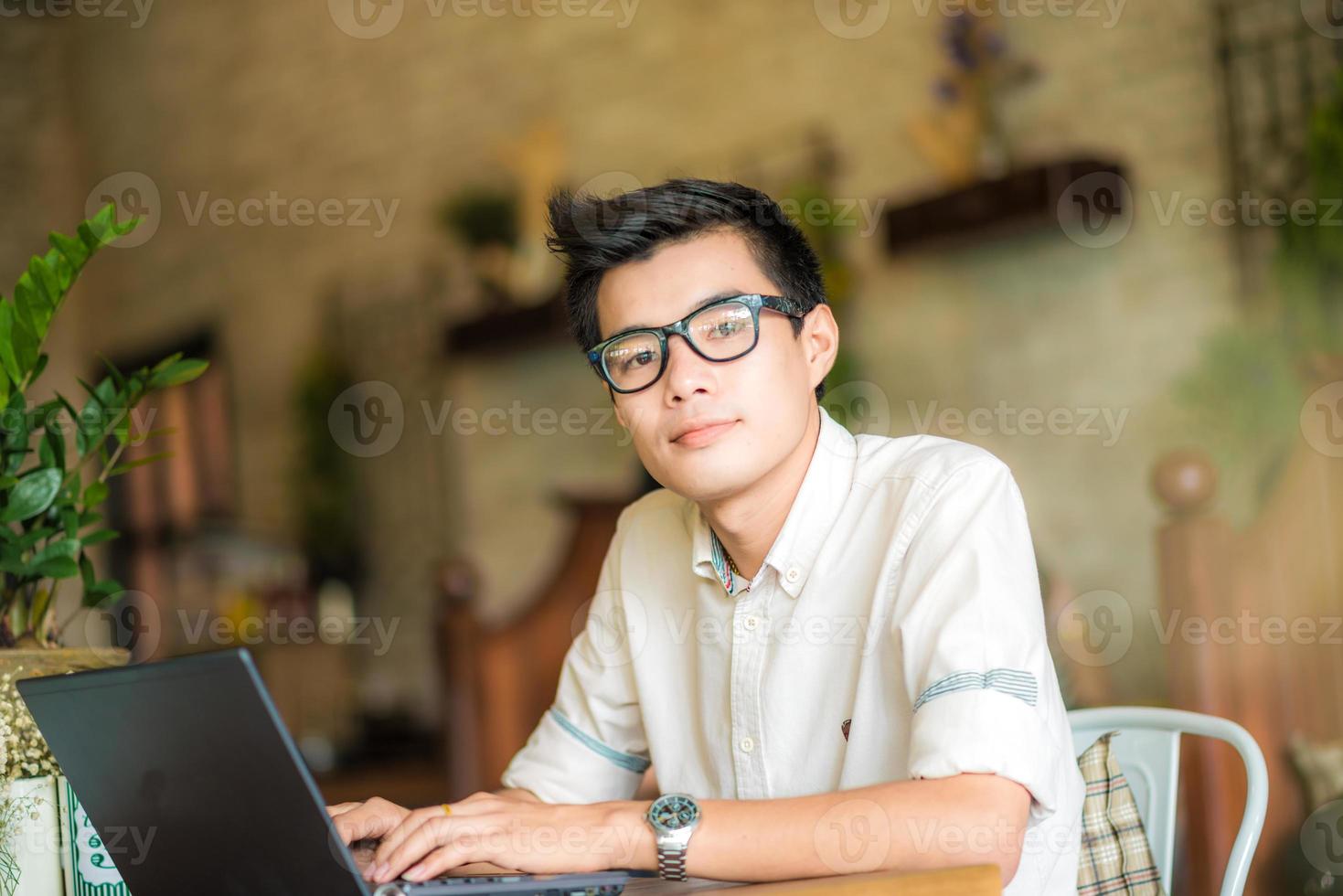 junger asiatischer Studentenmann, der Tablet-Computer im Café verwendet foto