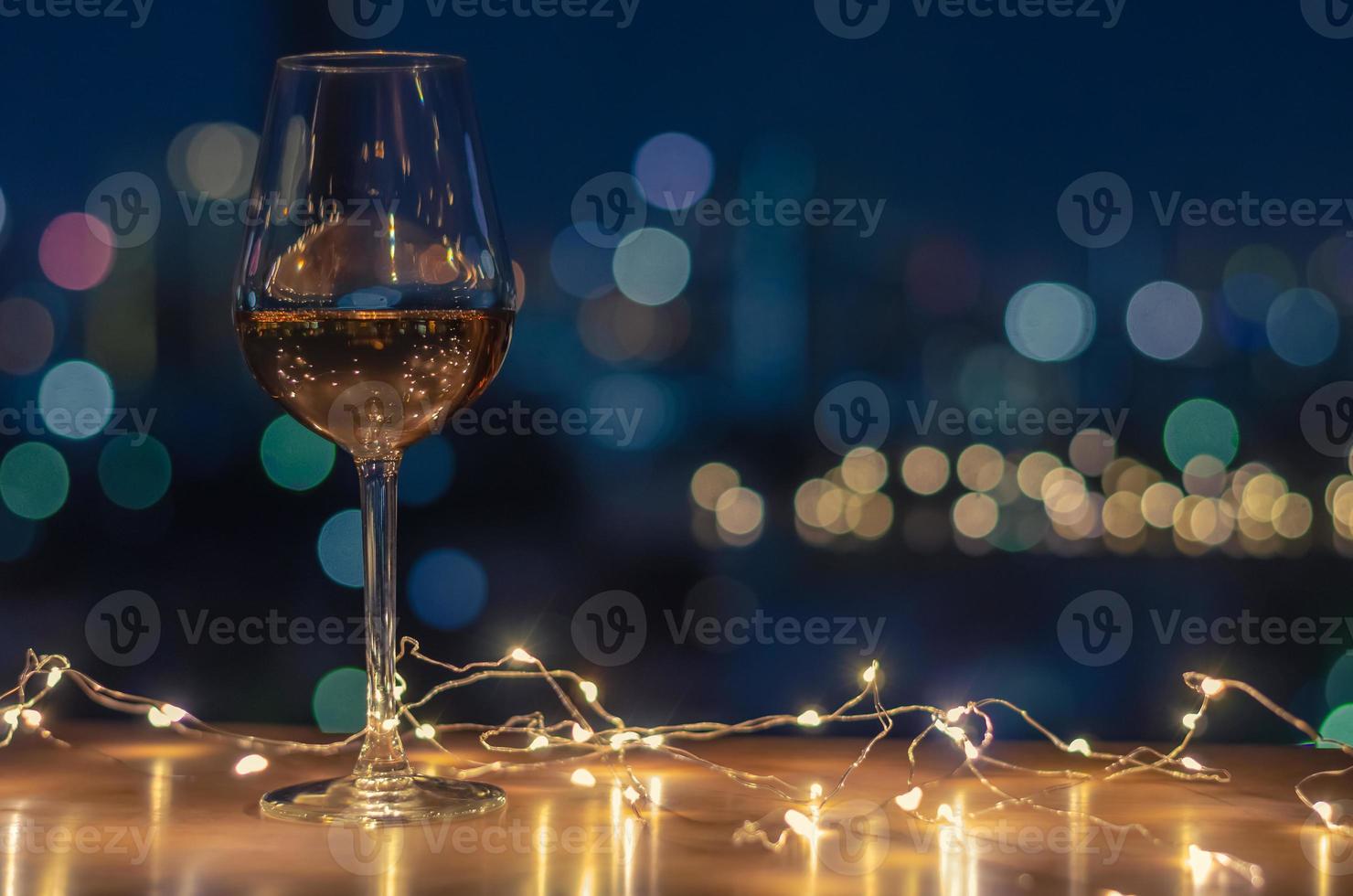 ein glas roséwein mit buntem stadt-bokeh-lichthintergrund. foto