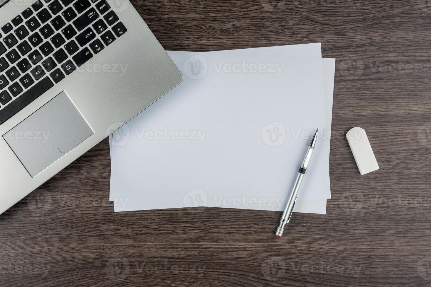 Laptop, Papierstift und Radiergummi auf dem Schreibtisch foto