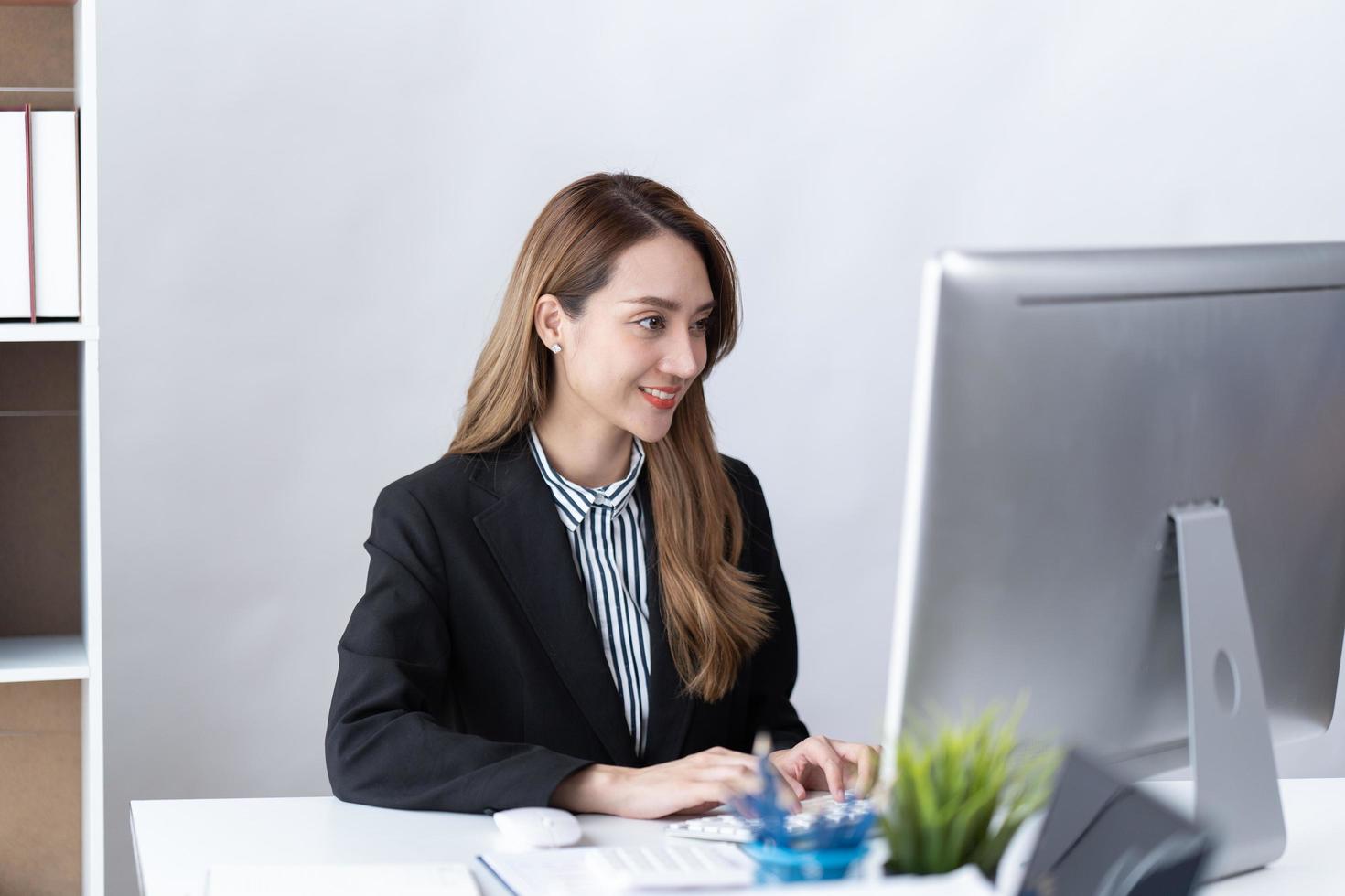 Das Porträt einer jungen asiatischen Geschäftsfrau arbeitet gerne im modernen Büro mit einem Laptop-Computer. geschäftsangestellter freiberuflicher online-marketing-e-commerce-telemarketing-konzept. foto