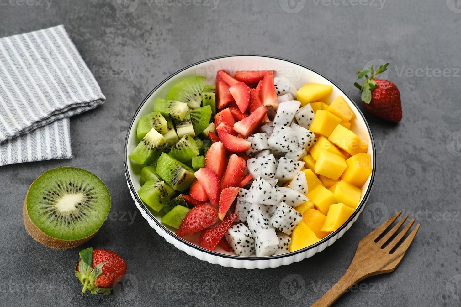 gesunde frische obstsalatschüssel, drachenfrucht, kiwi, mango, erdbeere, auf dem tisch. ausgewähltes Fokusbild. foto