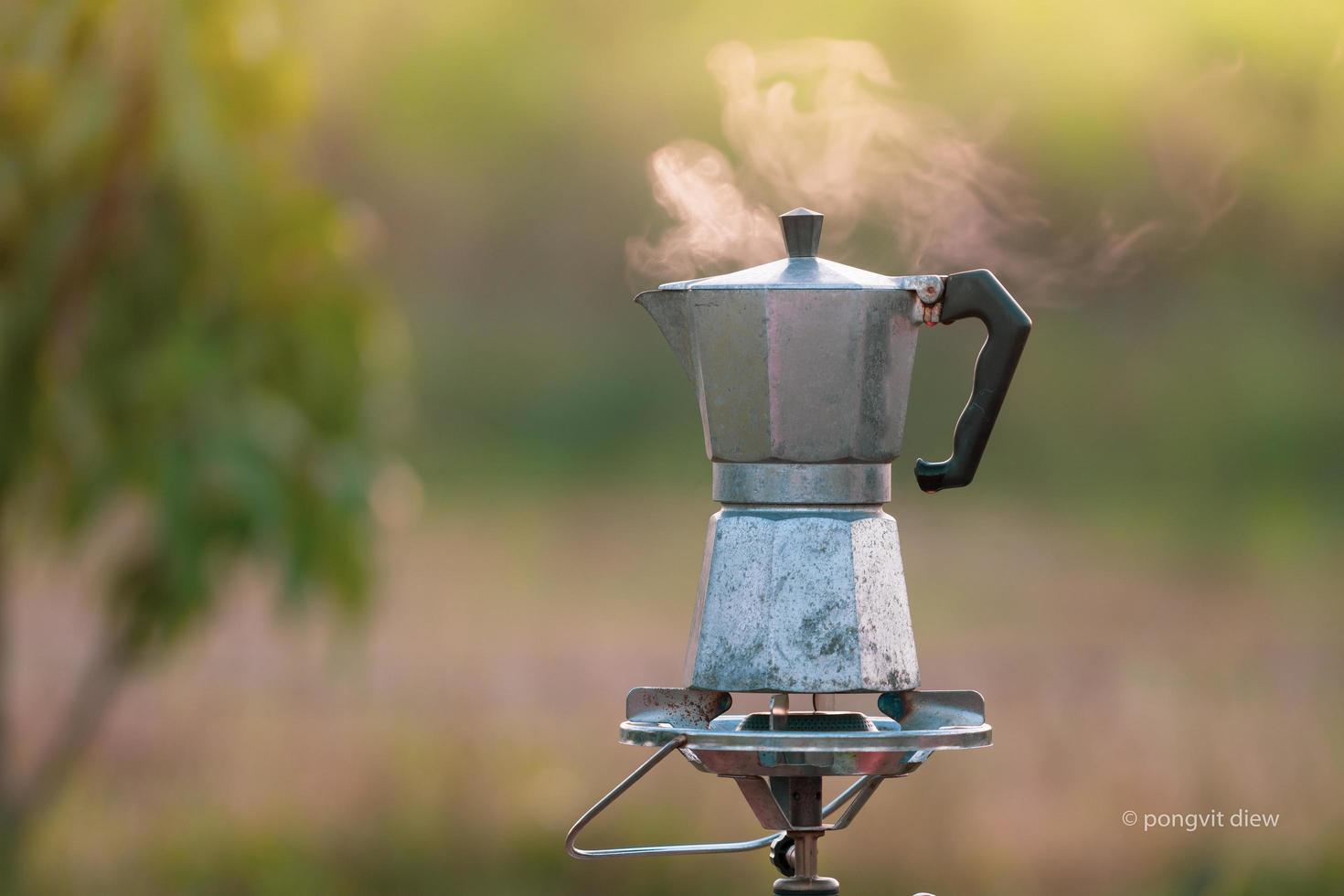 antike kaffee-moka-kanne auf dem gasherd zum camping, wenn die sonne morgens aufgeht. weicher fokus. foto