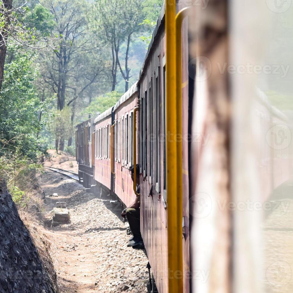 Spielzeugeisenbahn, die sich auf Berghängen bewegt, schöne Aussicht, ein Seitenberg, ein Seitental, das sich auf der Eisenbahn zum Hügel bewegt, inmitten grüner Naturwälder. Spielzeugeisenbahn von Kalka nach Shimla in Indien foto