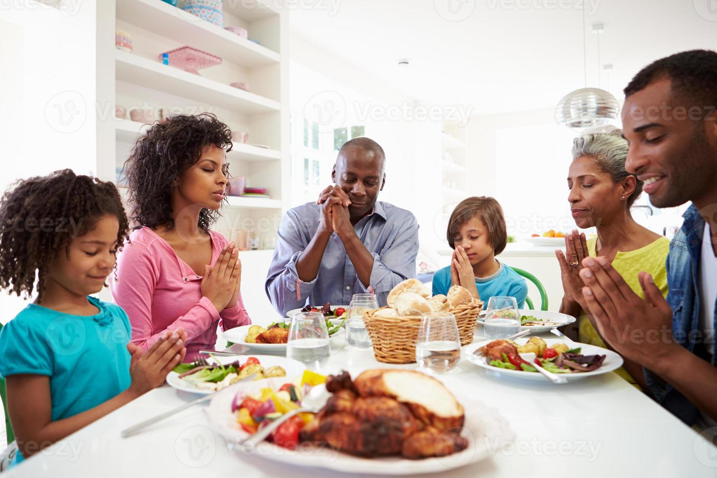 Afroamerikanerfamilie der mehreren Generationen, die zu Hause betet foto