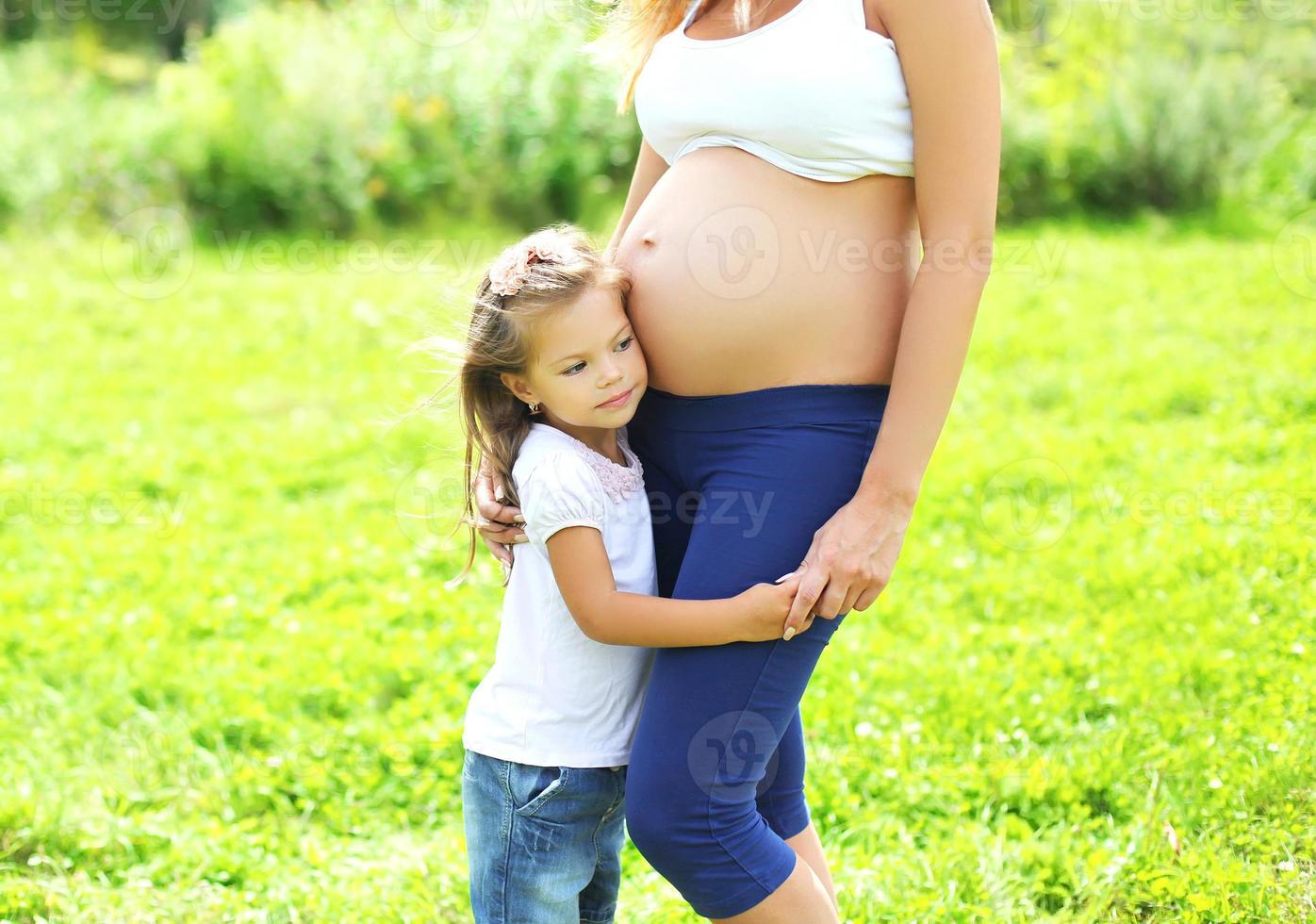 glückliche schwangere Frau, kleines Kind Tochter hört Bauch Mutter foto