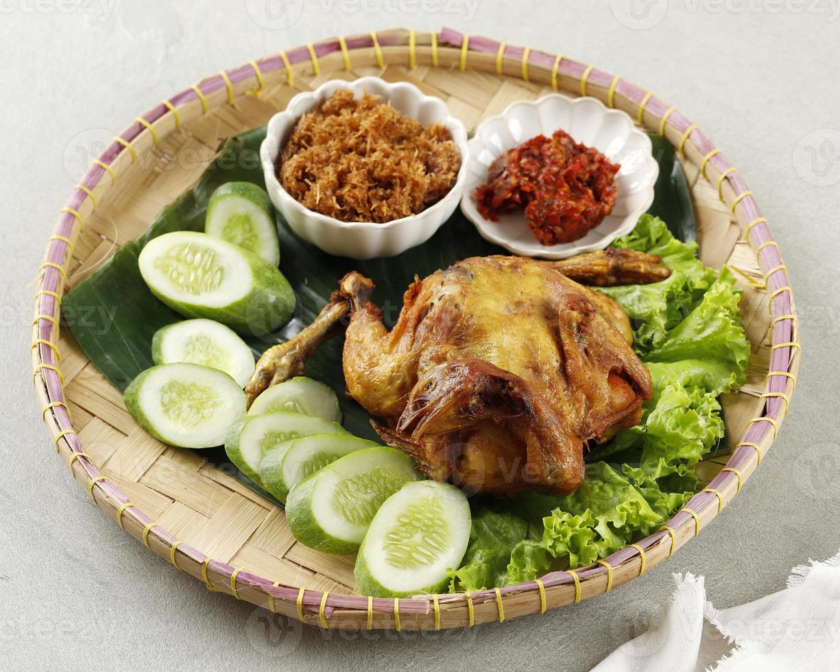 ayam goreng utuh. frittiertes ganzes Hühnchen, serviert mit Sambal-Chili-Paste und frischem Gemüse. foto