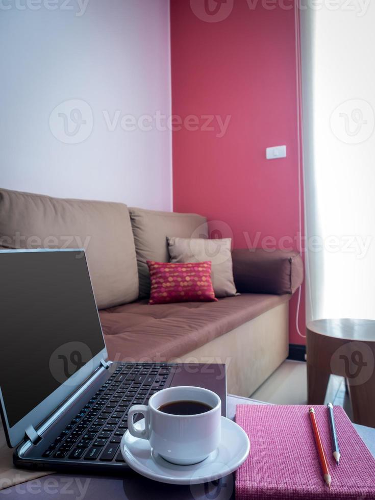 Laptop mit Kaffeetasse auf der Couch im modernen Wohnzimmer foto
