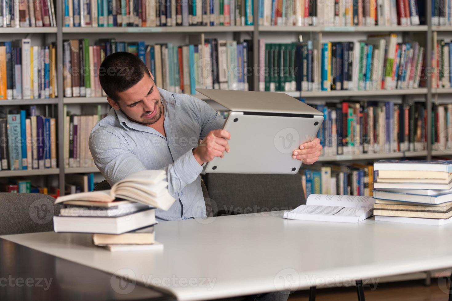 wütender Student, der seinen Laptop wegwirft foto