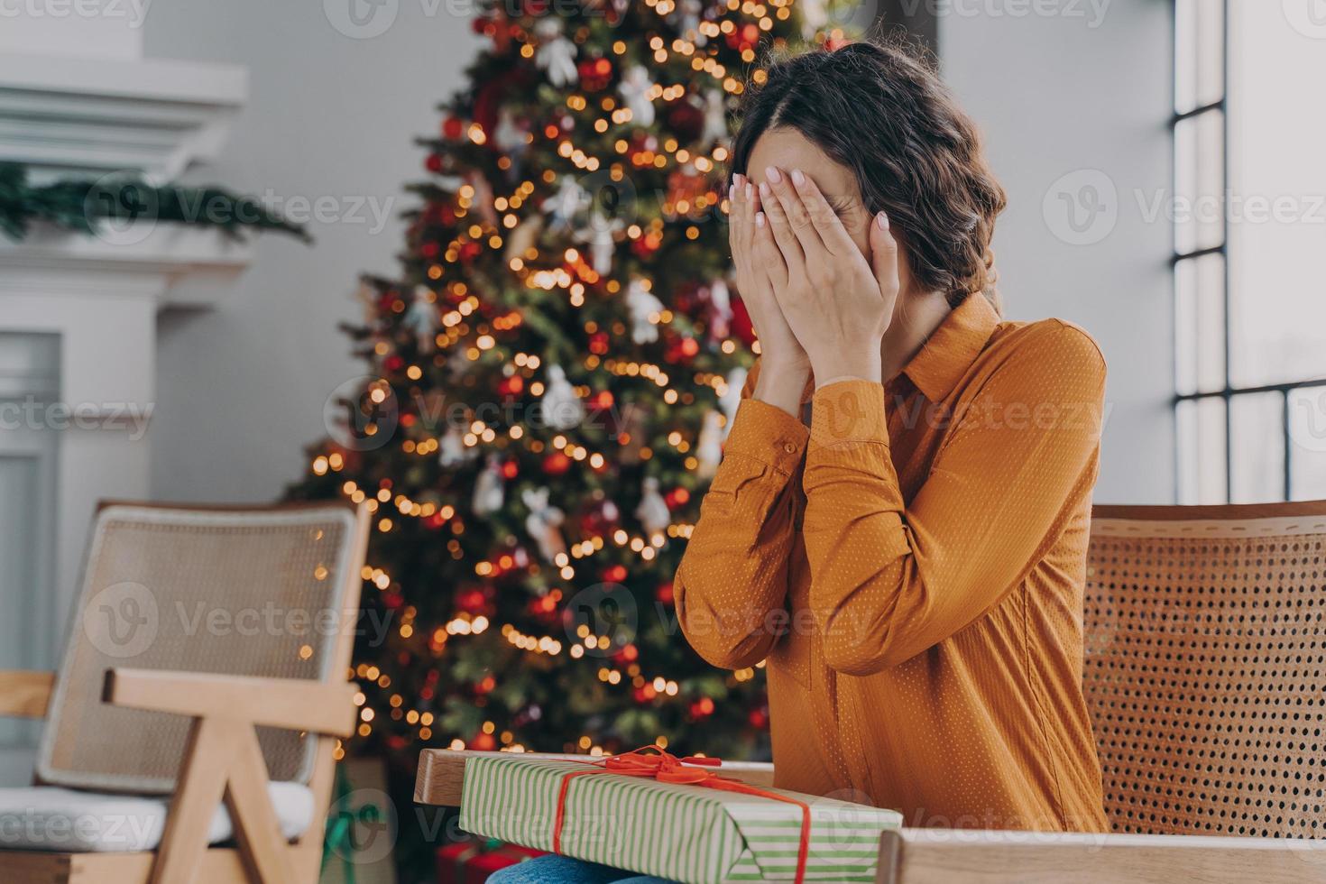 neugierige frau, die augen mit händen bedeckt und errät, was sich in der weihnachtsgeschenkbox befindet foto