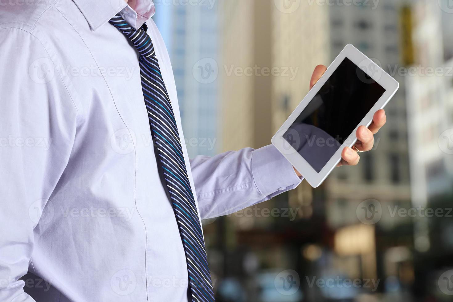 Geschäftsmann, der das digitale Tablet im Büro hält und benutzt foto