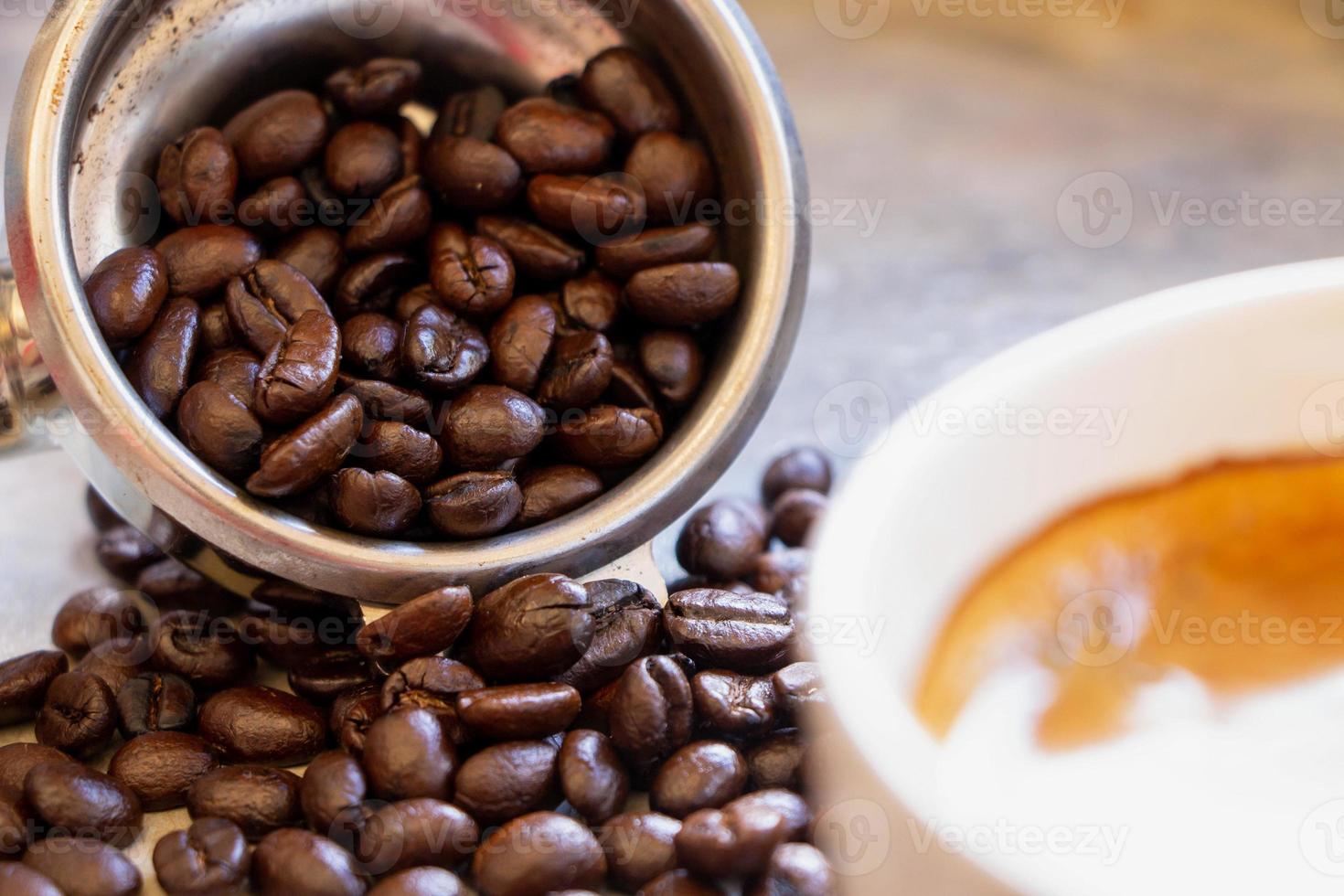 Nahaufnahme des Filterhalterkorbs mit organischen dunkelbraunen gerösteten Arabica-Kaffeebohnen im Inneren. foto