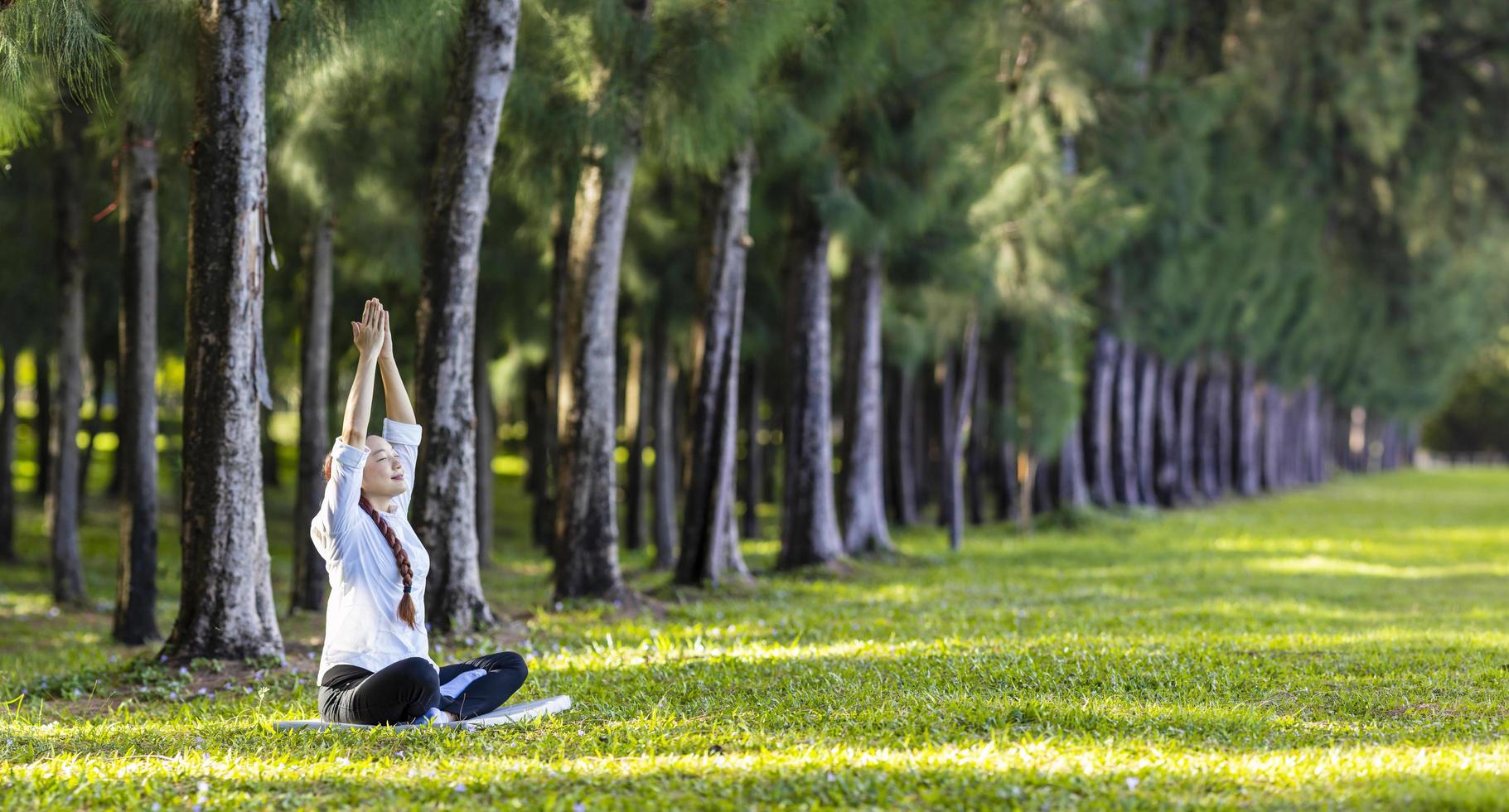 Frau, die entspannend Yoga-Meditation im Kiefernwald praktiziert, um Glück aus innerer Friedensweisheit für ein gesundes Geist- und Seelenkonzept zu erlangen foto