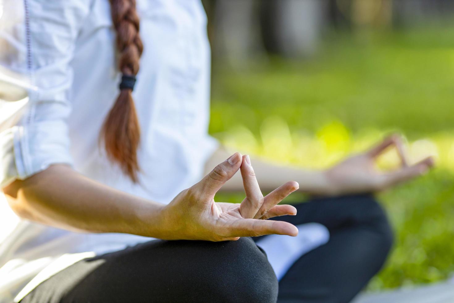 Frau, die Yoga im Freien in ruhiger Natur praktiziert, mit einer einfachen und einfachen Position, um das Ein- und Ausatmen in Meditationshaltung zu kontrollieren foto