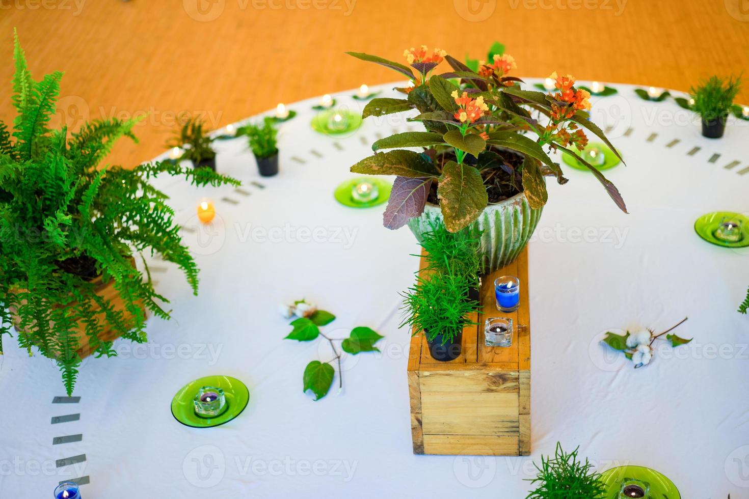 kerzendekoration auf dem holzfluss mit blumenfarn und baum auf weißem kreis in der mitte der holzbodenmitte in der halle. foto