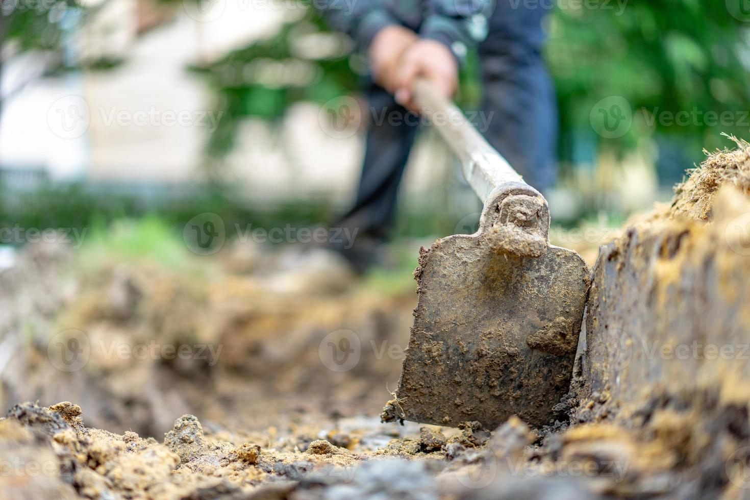 gärtner gräbt den boden mit seiner ausrüstung für die gartenarbeit und bereitet land für die bepflanzung vor. foto