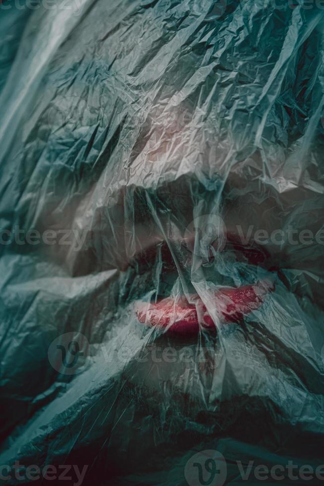 Frau, deren Gesicht mit einer Plastikfolie bedeckt ist foto