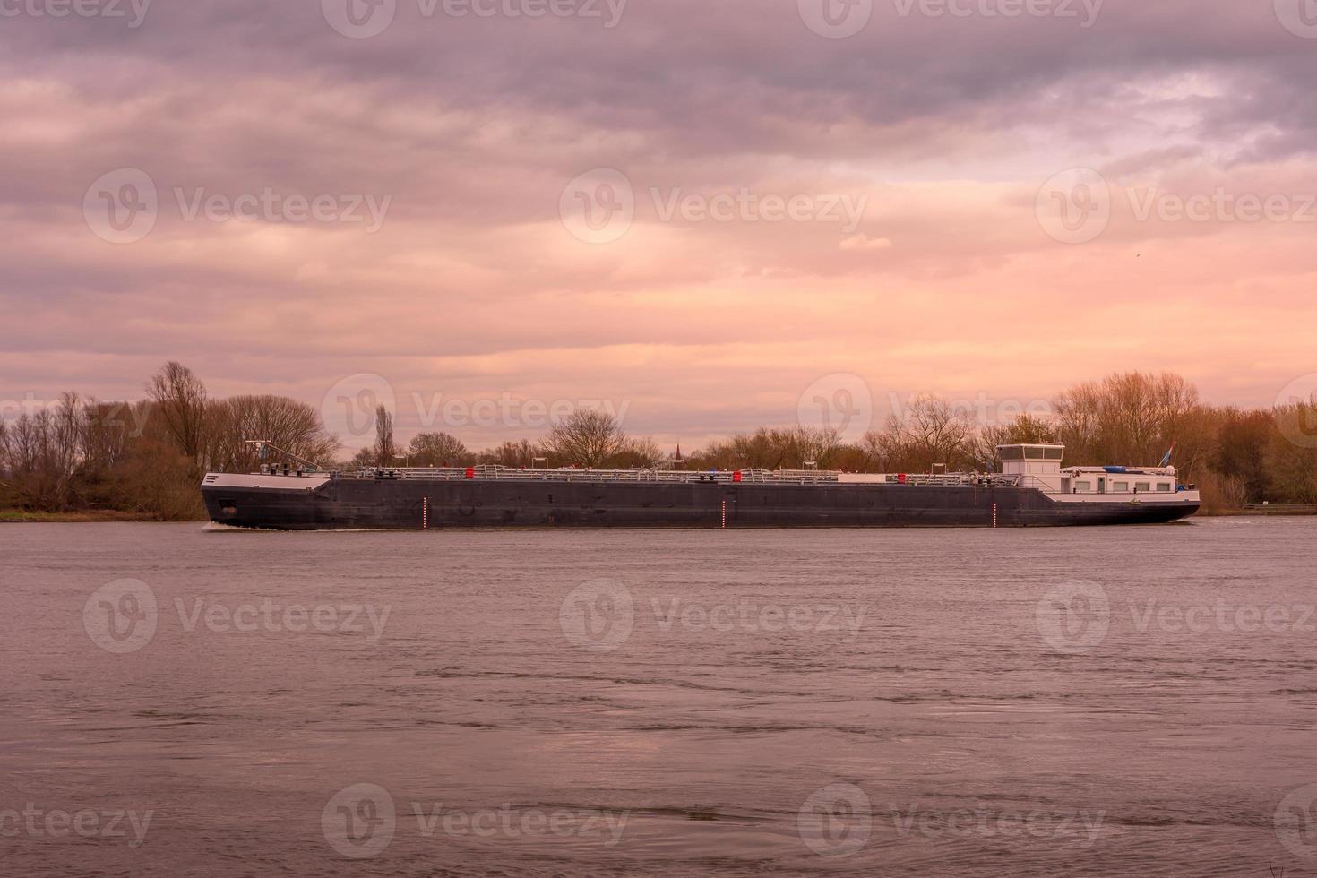 Ein großes Frachtschiff auf einem Fluss im Sonnenuntergang foto
