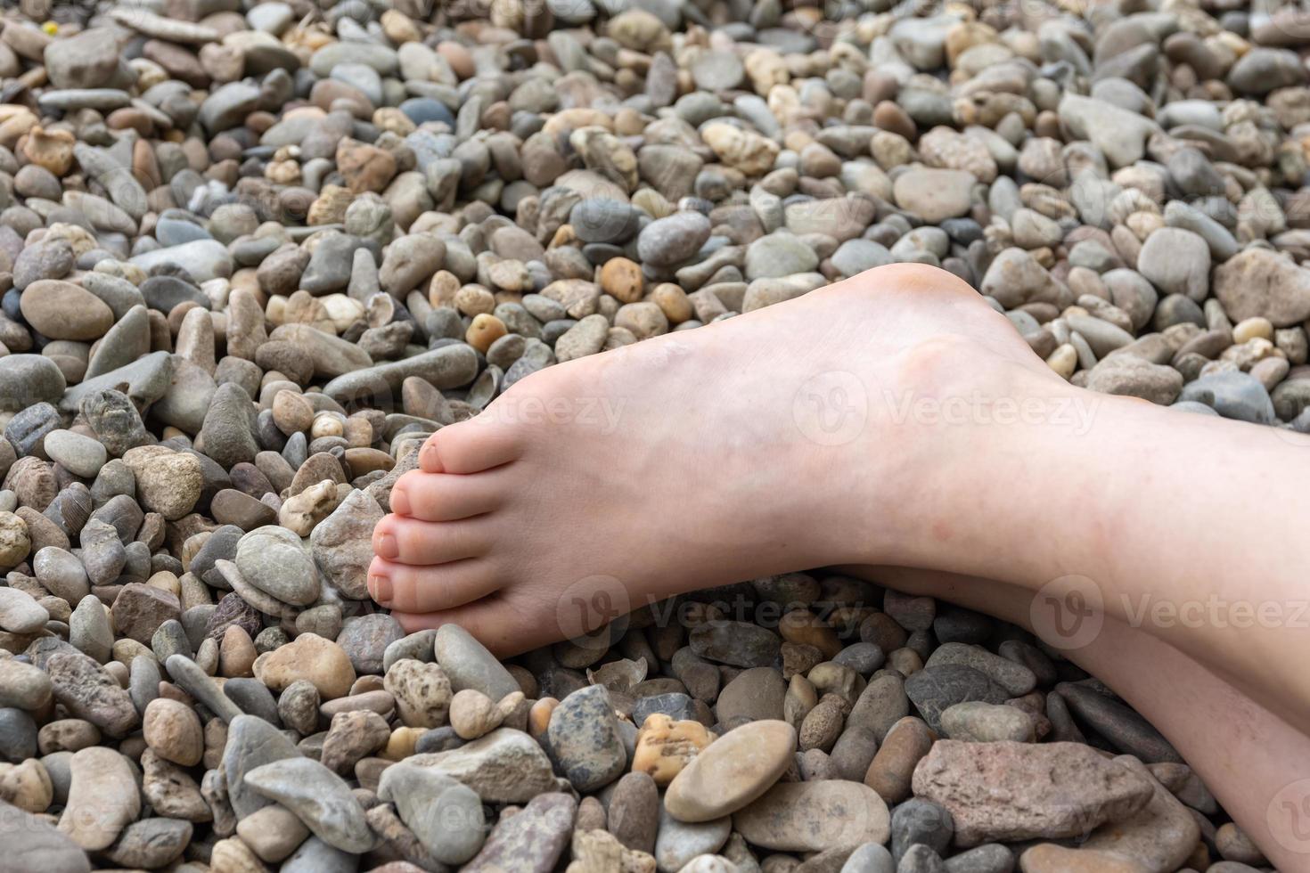 Teilansicht eines menschlichen nackten Fußes auf Kieselsteinen foto