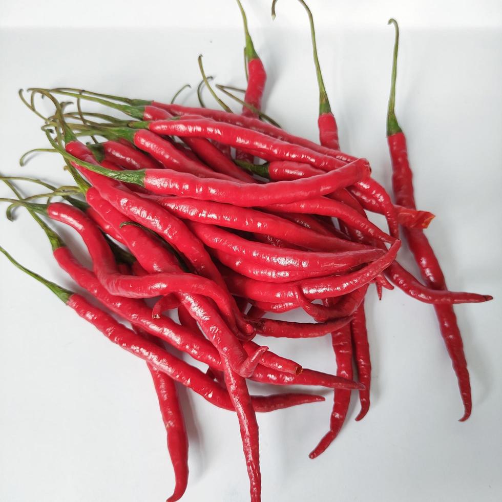 ein Haufen frischer langer roter Chilis mit weißem Hintergrund foto