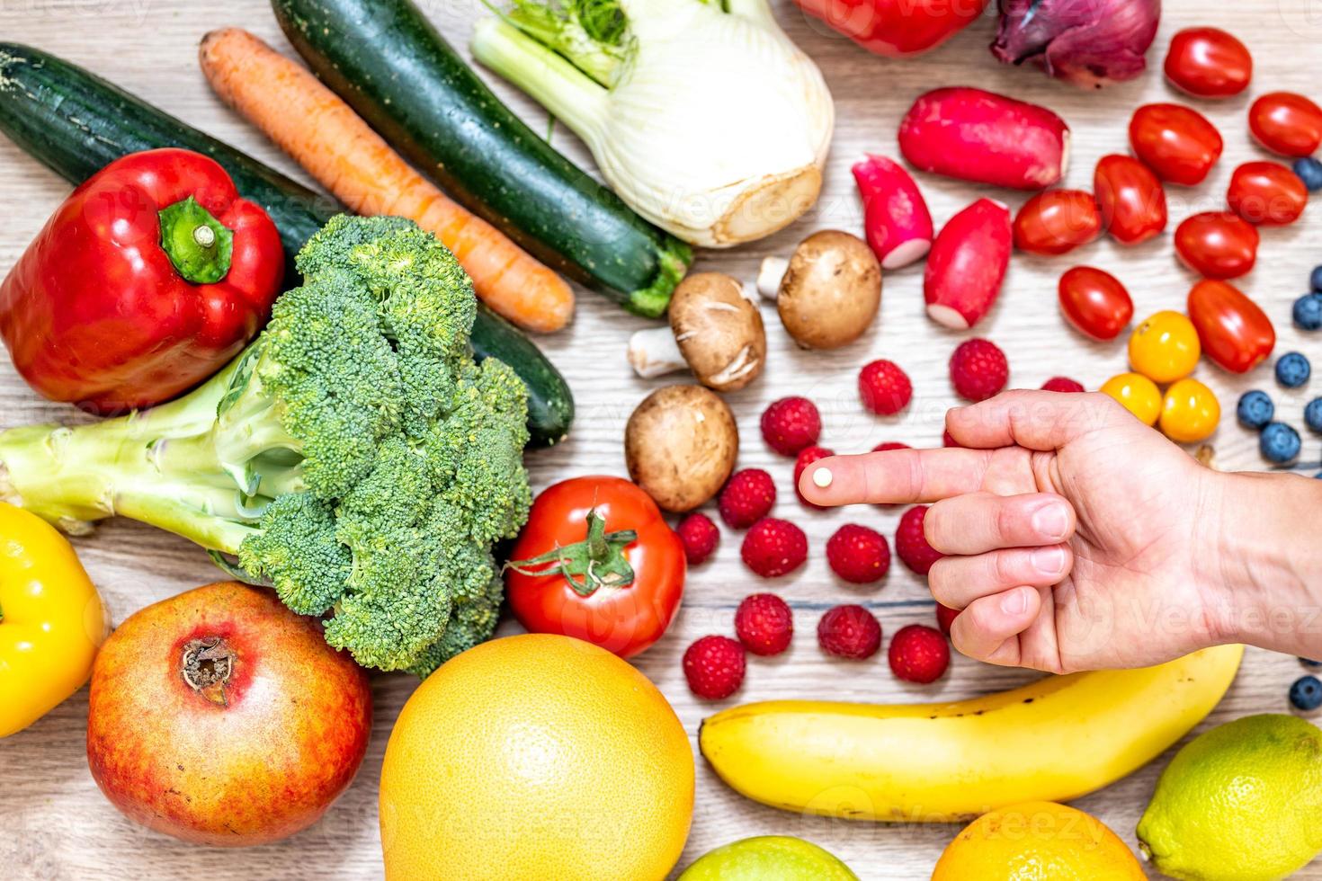 hand, die nahrungsergänzungsmittel über gemüse und obst für einen gesunden lebensstil hält foto