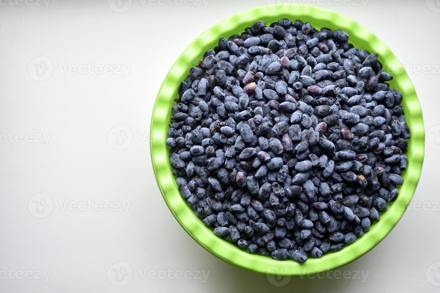 Früchte von Geißblattbeeren in einem Becken auf weißem Hintergrund foto