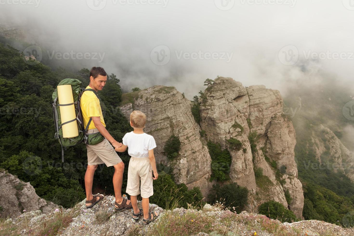 Backpacker mit kleinem Sohn in den nebligen Bergen. foto