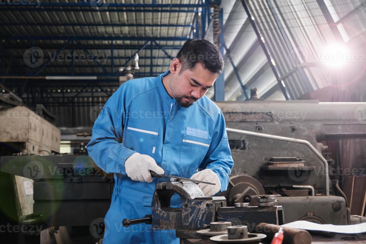 ein professioneller asiatischer männlicher industrieingenieur arbeitet in einer sicherheitsuniform mit metallbearbeitungspräzisionswerkzeugen, mechanischen drehmaschinen und einer ersatzteilwerkstatt in der stahlfabrik. foto