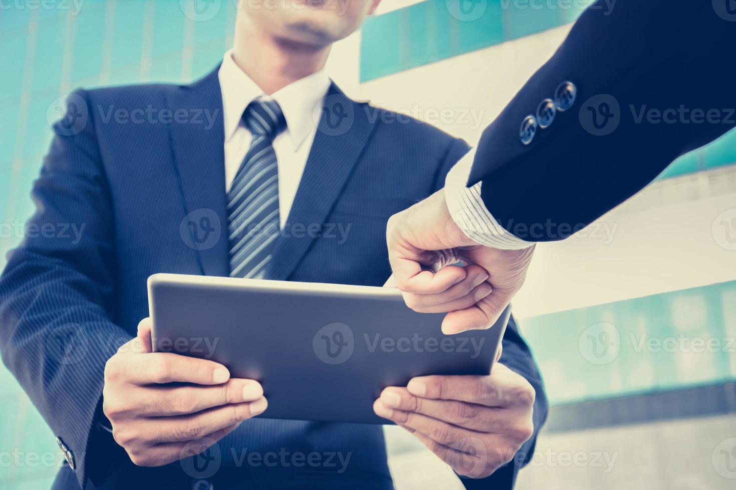 Geschäftsleute, die Tablet-PC mit einem Handberührungsbildschirm betrachten foto