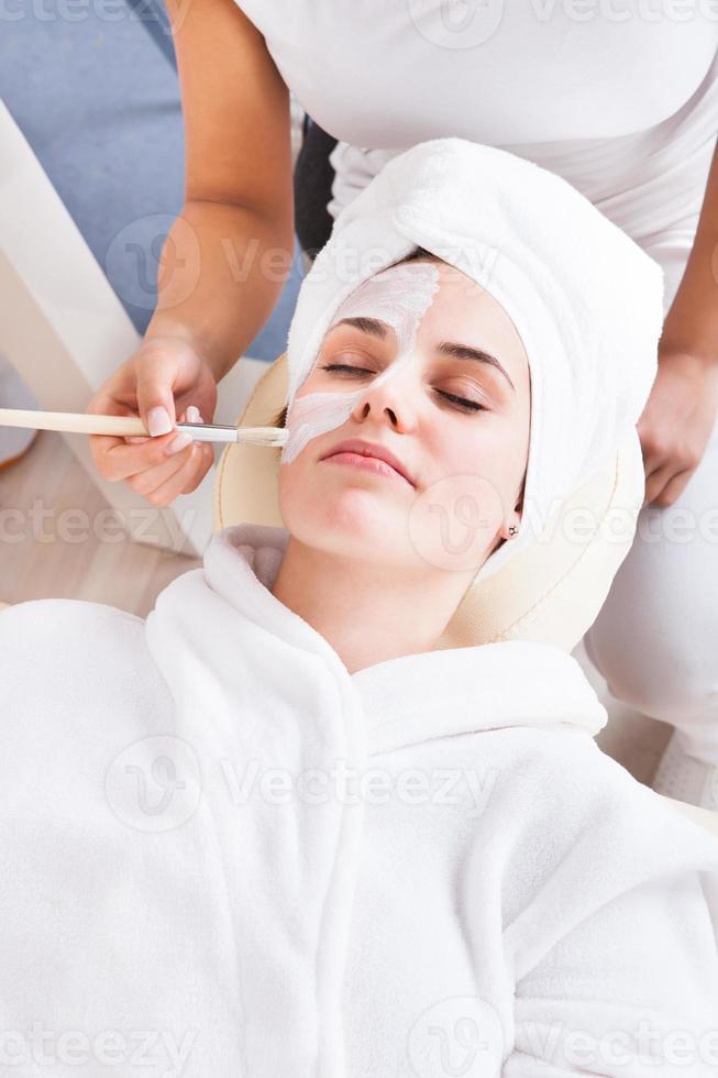 Therapeut, der Gesichtsmaske auf Frau anwendet foto