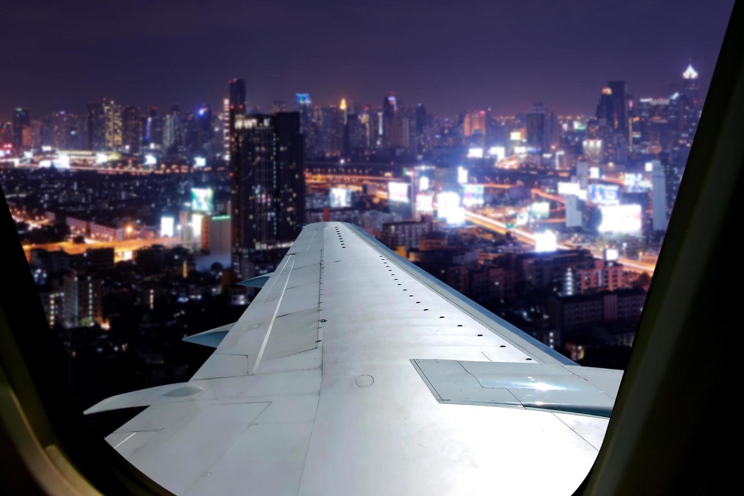 Abendflug am Dämmerungshimmel, tolle Aussicht aus dem Fensterflugzeug. Fensterplatz im Flugzeug mit Blick auf die Stadt bei Nacht. foto