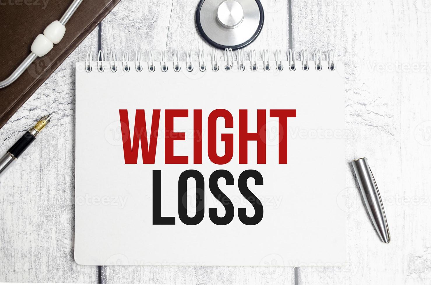 Gewichtsverlustwörter auf Notizblock und Stethoskop foto