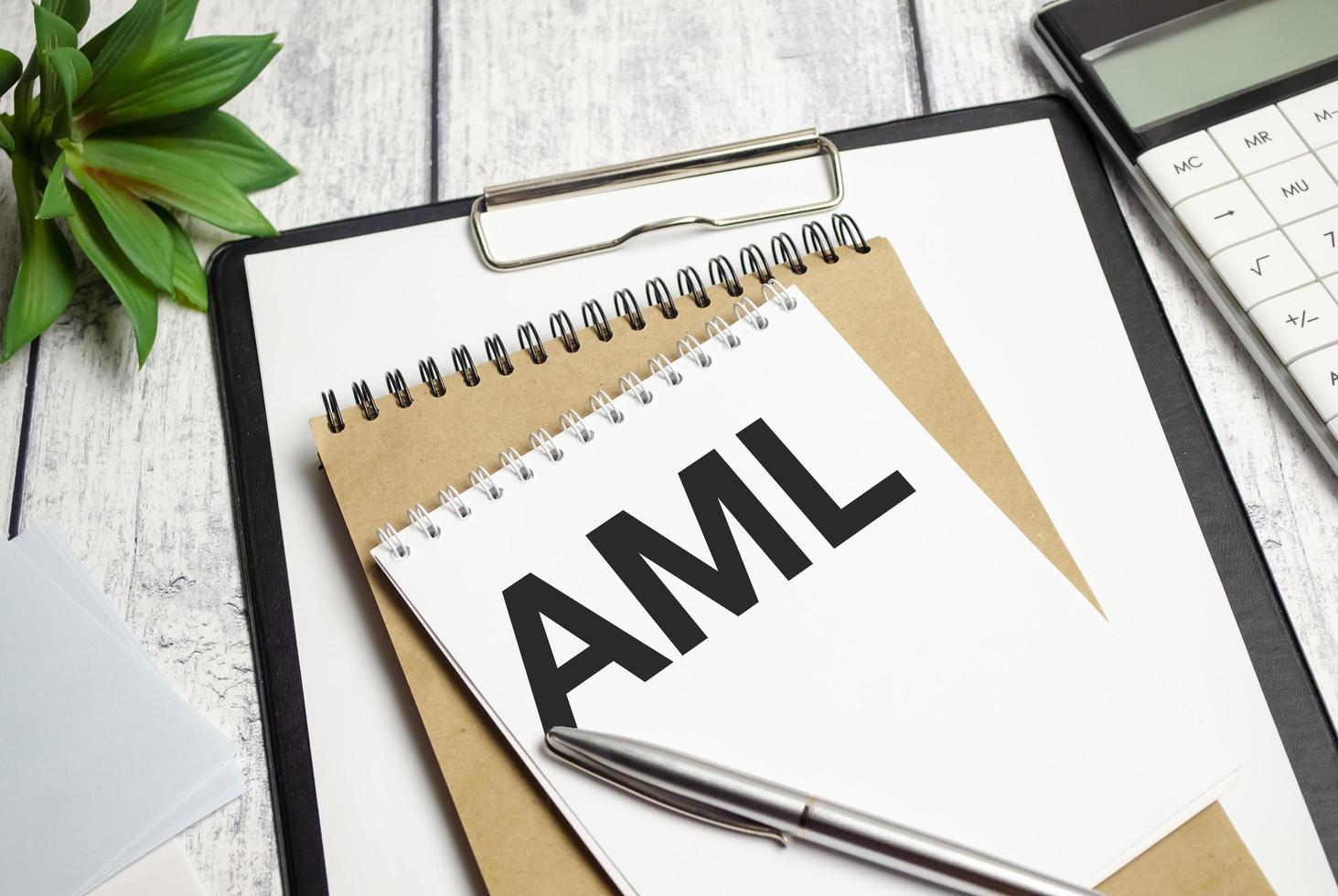 auf dem holzschreibtisch liegt ein blatt papier mit der aufschrift - aml gegen geldwäsche foto