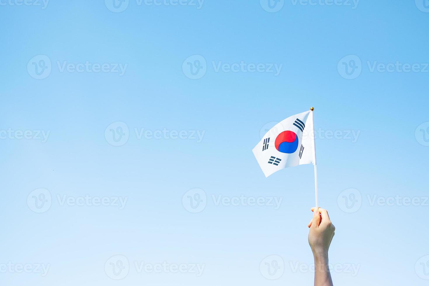 Hand, die Korea-Flagge auf Naturhintergrund hält. nationale stiftung, gaecheonjeol, öffentlicher nationalfeiertag, nationaler befreiungstag koreas und fröhliche feierkonzepte foto